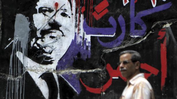 A man walks past graffiti depicting ousted Egyptian President Mohamed Mursi in downtown Cairo September 2, 2013. Egypt&#039;s army-backed authorities referred deposed Mursi to trial on Sunday on charges of inciting murder and violence, in an escalation of the crackdown on his Muslim Brotherhood. The Arabic words read: &quot;Red card, 30 June&quot; REUTERS/Amr Abdallah Dalsh (EGYPT - Tags: POLITICS CIVIL UNREST)