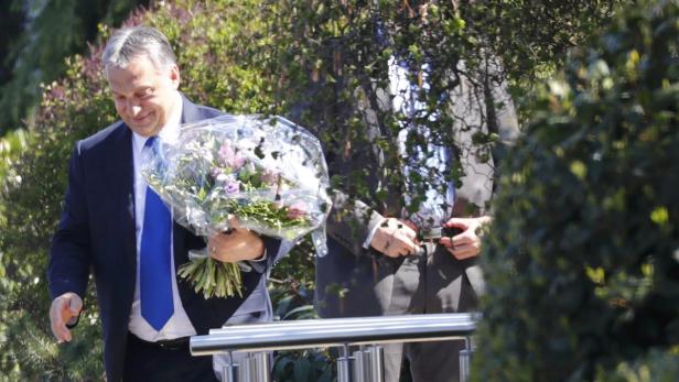 Viktor Orbán mit einem Blumenstrauß in der Hand.