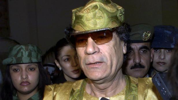 Libyan leader Muammar Gaddafi stands surrounded by his female bodyguards and speaks to reporters as he leaves an Arab summit in Amman March 28, 2001. Arab leaders pledged funds for Palestinians fighting Israeli rule and edged towards reviving a boycott of Israel on Wednesday, but failed to agree on the devisive issue of Iraq. REUTERS/Jamal Saidi