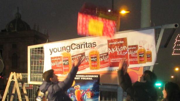Menschen werfen ein Paket vor einem „Young Caritas“-Plakat in die Luft.