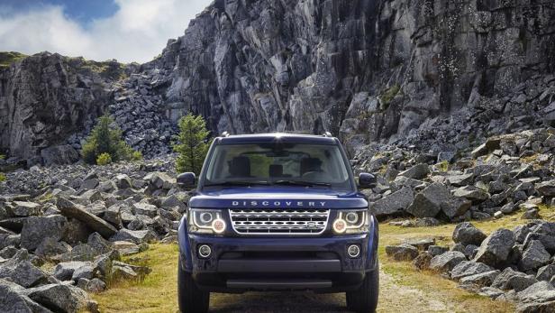 Ein blauer Land Rover Discovery steht vor einer felsigen Berglandschaft.