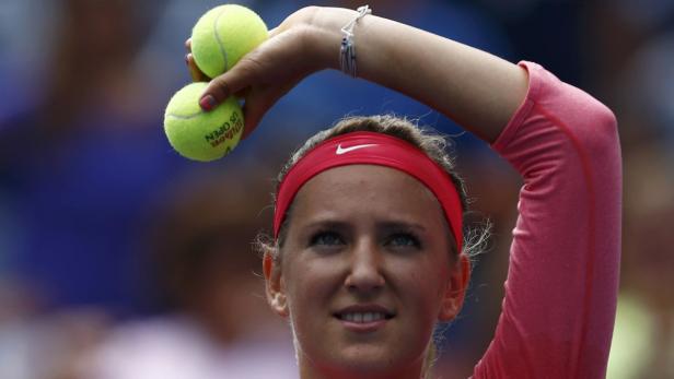 Eine Tennisspielerin mit rotem Stirnband hält zwei Tennisbälle in der Hand.