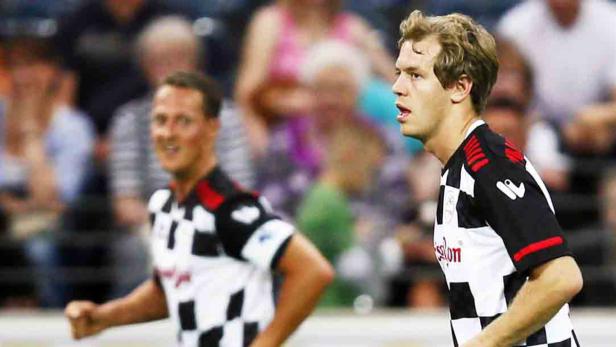 Zwei Männer in Schachbrett-Trikots stehen auf einem Sportplatz.