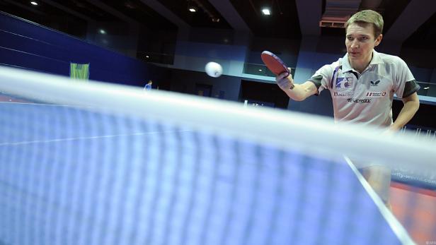 Ein Tischtennisspieler schlägt den Ball über das Netz.