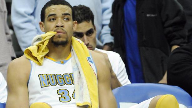 Ein Basketballspieler der Denver Nuggets sitzt mit einem Handtuch um den Hals auf der Bank.