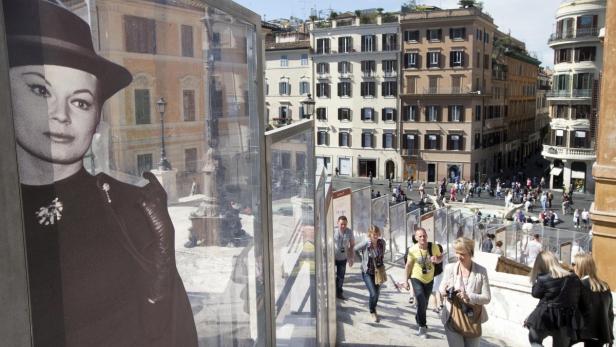 Blick auf die Spanische Treppe in Rom mit einer Ausstellung historischer Schwarz-Weiß-Porträts.
