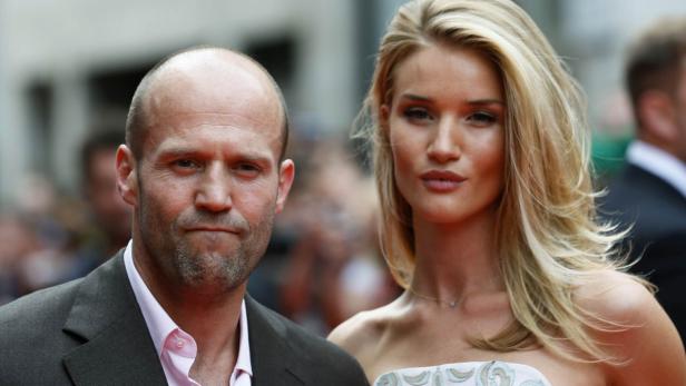 Jason Statham und Rosie Huntington-Whiteley posieren auf einem roten Teppich.
