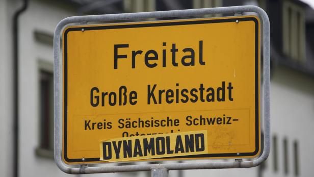 Ein gelbes Ortsschild von Freital, Große Kreisstadt, mit einem „Dynamoland“-Aufkleber.