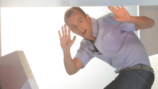 Ein Mann in Jeans und Hemd hält beschwichtigend die Hände hoch.