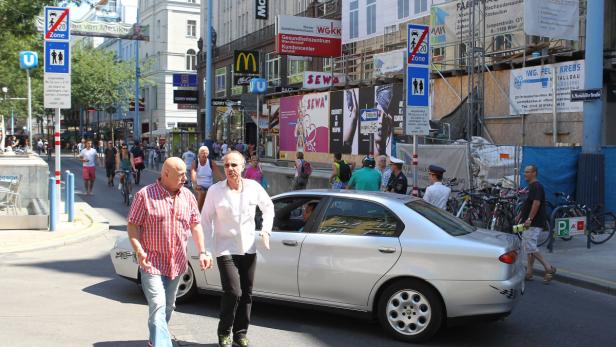Zwei Männer überqueren eine Straße in Wien, im Hintergrund die Mariahilfer Straße.