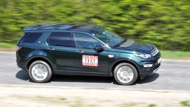 Ein grüner Land Rover Discovery Sport fährt auf einer Straße.