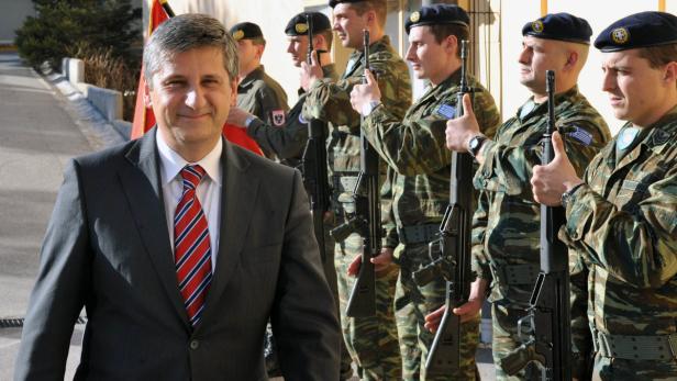 Ein Mann im Anzug steht vor einer Reihe von Soldaten in Uniform.