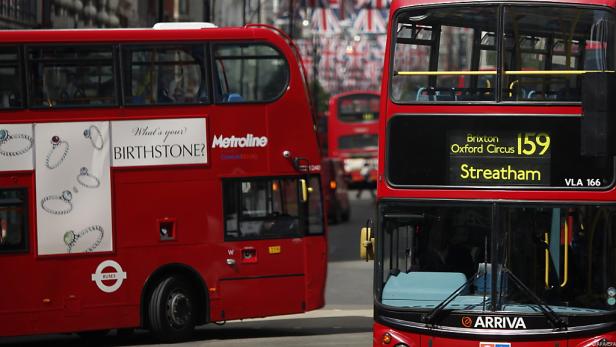 Zwei rote Doppeldeckerbusse in London, einer mit Werbung für Geburtssteine.