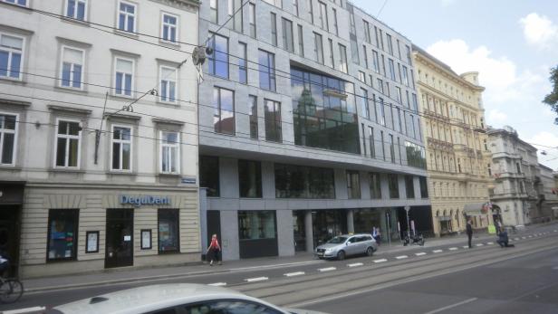 Eine Straße in Wien mit verschiedenen Gebäuden und einer Straßenbahnlinie.