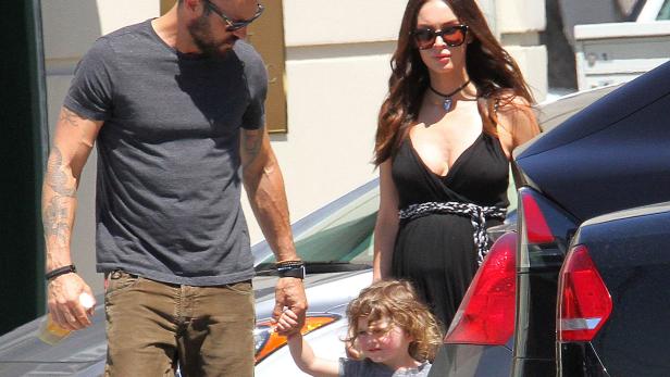 Megan Fox mit ihrem Mann und ihrem Kind in der Nähe eines Autos.