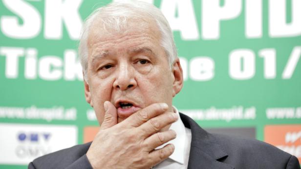 Ein älterer Mann mit grauem Haar spricht und hält seine Hand an sein Kinn.