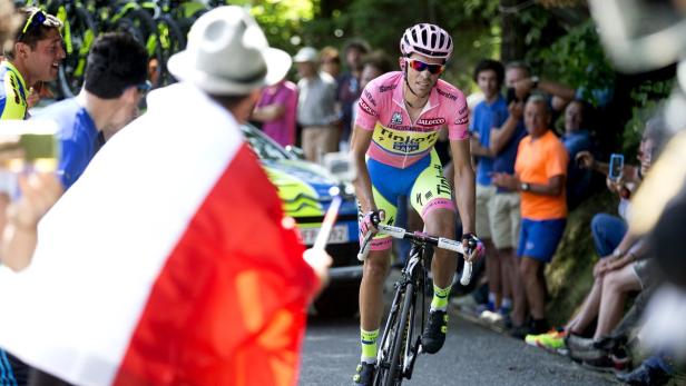 Ein Radfahrer in Rosa fährt an einer Menschenmenge mit einer polnischen Flagge vorbei.