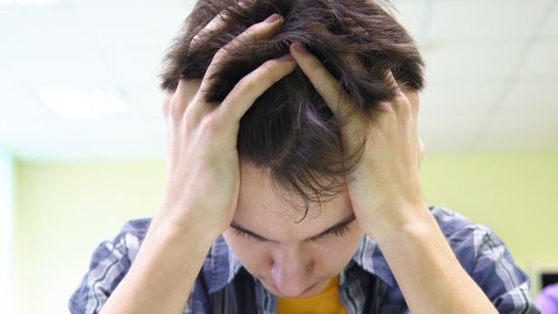 student put his hands over his head bent notebook on exam