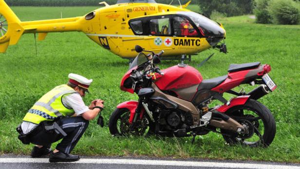 Ein Polizist untersucht ein rotes Motorrad vor einem gelben Rettungshubschrauber.