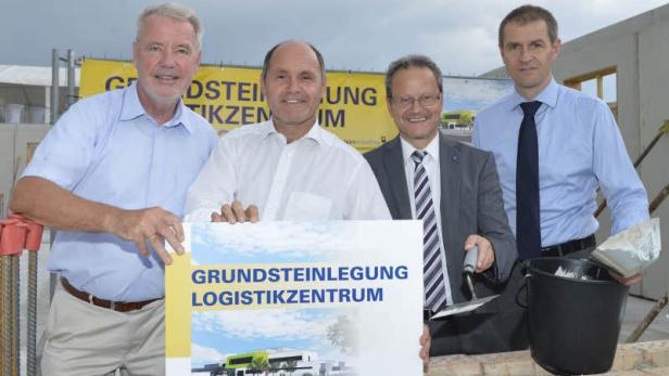 Vier Männer posieren bei der Grundsteinlegung für ein Logistikzentrum.