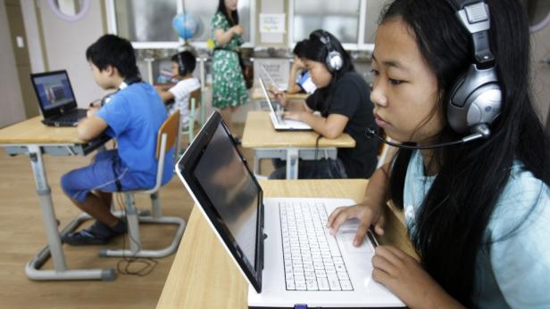 Schüler arbeiten mit Laptops und Headsets in einem Klassenzimmer.