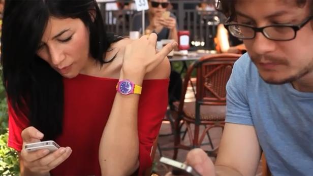 Eine Frau mit rotem Oberteil und eine Mann mit blauem T-Shirt schauen auf ihre Smartphones.