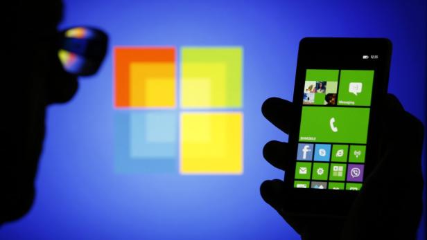 Ein Windows Phone wird vor dem Microsoft-Logo gehalten.