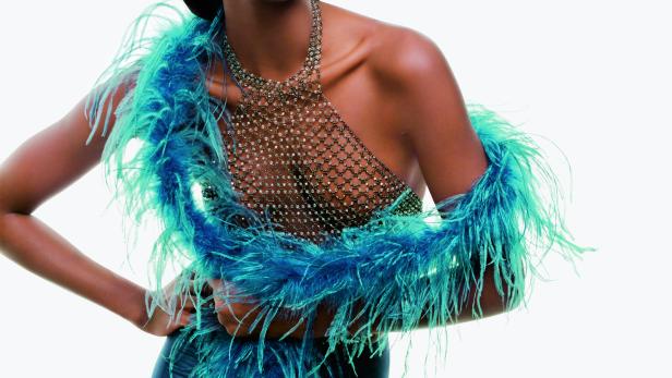 Eine Frau mit dunkler Haut trägt eine blaue Federboa und ein glitzerndes Oberteil.