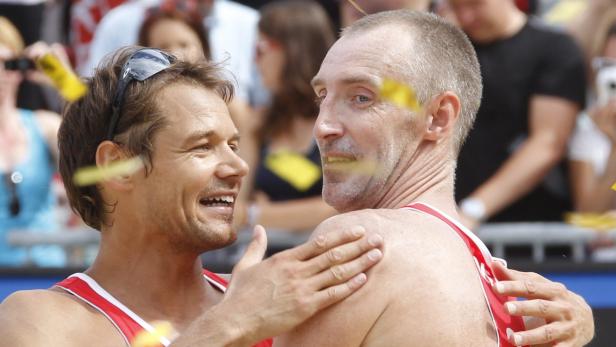 Zwei Beachvolleyballspieler umarmen sich und feiern einen Sieg.