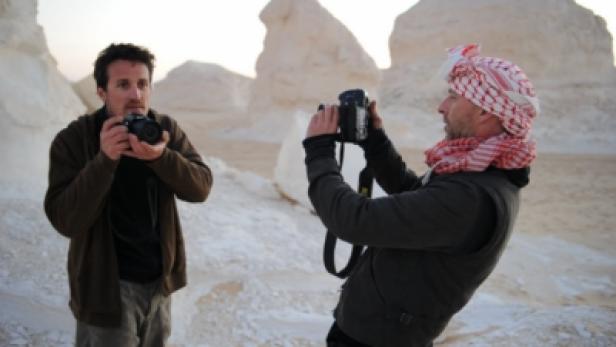 Zwei Männer fotografieren in einer Wüstenlandschaft mit bizarren Felsformationen.