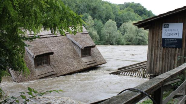 Ein Haus mit Reetdach ist von Hochwasser umgeben.