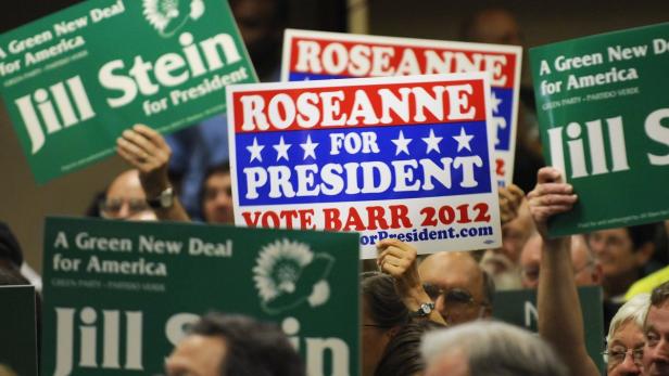 Menschen halten Wahlplakate für Jill Stein und Roseanne Barr bei einer Wahlveranstaltung.