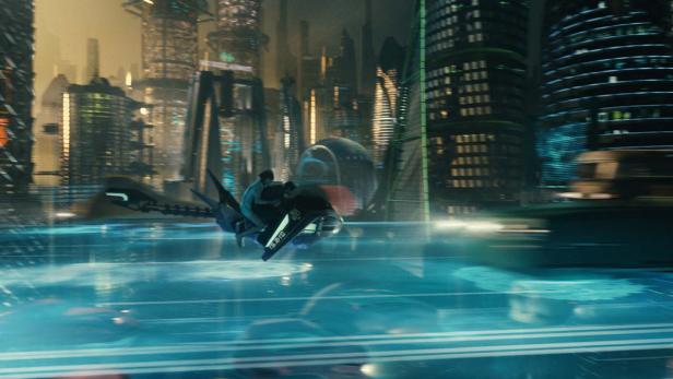 Zwei Personen fliegen mit einem futuristischen Fahrzeug durch eine Stadt.