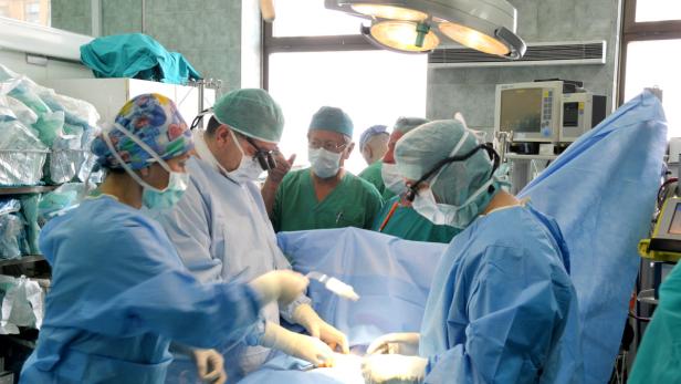 Ein Operationsteam führt eine Operation in einem hell erleuchteten Operationssaal durch.