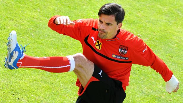 Ein österreichischer Fußballspieler dehnt sich auf einem grünen Rasen.