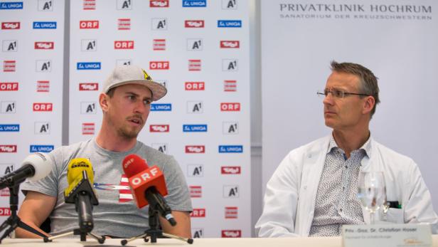 Ein Sportler und ein Arzt sitzen vor Mikrofonen in der Privatklinik Hochrum.
