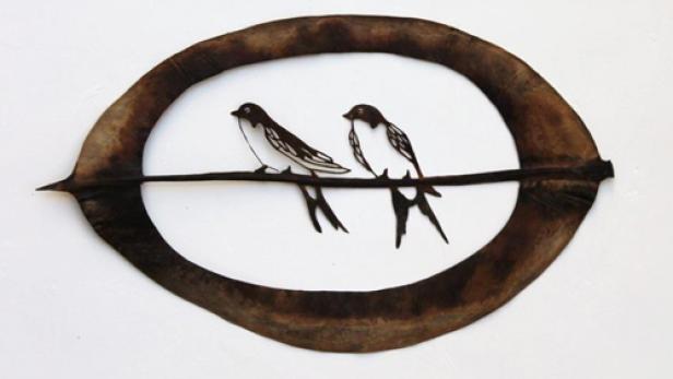 Zwei stilisierte Schwalben sitzen auf einem Ast, umrahmt von einem Blatt.