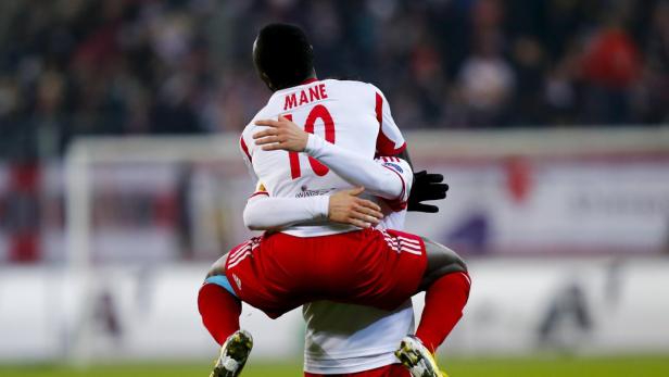 Ein Fußballspieler mit der Nummer 10 und dem Namen Mané wird von einem Teamkollegen umarmt.