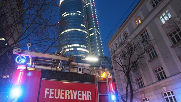 Ein rotes Feuerwehrfahrzeug steht vor einem hohen Gebäude bei Nacht.