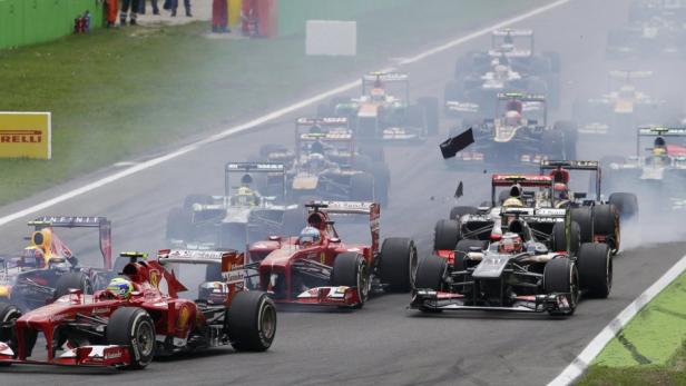 Mehrere Formel-1-Autos fahren auf einer Rennstrecke, Rauch steigt auf.