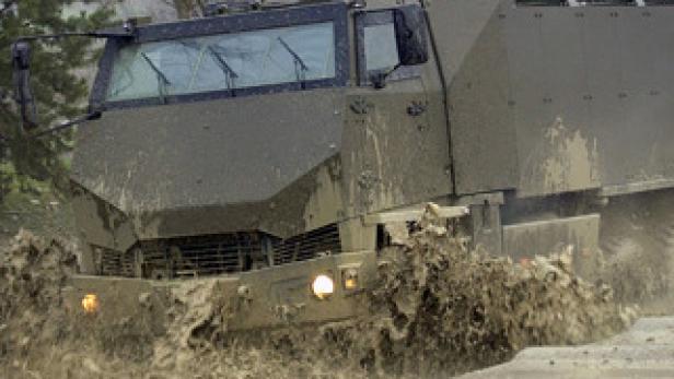 Ein Militärfahrzeug fährt durch schlammiges Wasser.