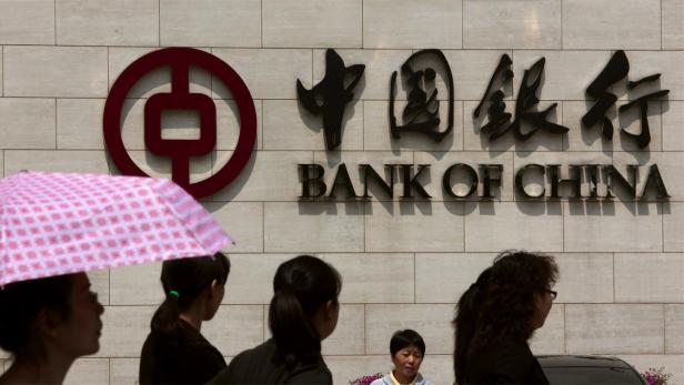 Menschen gehen vor der Fassade der Bank of China entlang.