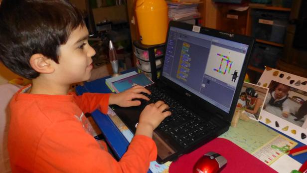 Ein Junge programmiert ein Spiel auf einem Laptop.