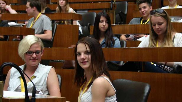 Junge Leute sitzen in einem holzvertäfelten Raum, möglicherweise bei einer Konferenz oder einer Schulung.