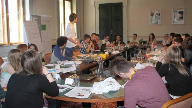 Eine Gruppe junger Leute sitzt an einem Tisch während einer Präsentation.