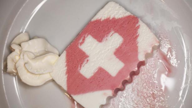 Ein Stück Dessert mit Schweizerkreuz-Muster und einer Beilage Schlagsahne.