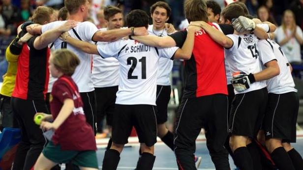 Eine Gruppe von Floorball-Spielern umarmt sich auf dem Spielfeld.