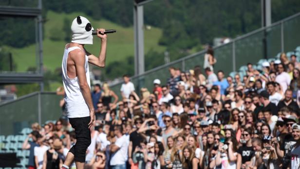 Ein Sänger mit Panda-Maske tritt vor einem großen Publikum auf.