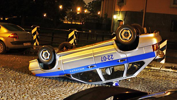 Ein umgekippter russischer Polizeiwagen liegt auf einem Kopfsteinpflaster.