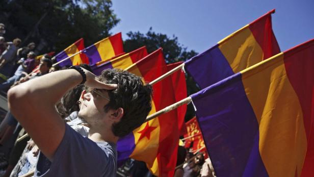 Ein Mann blickt in die Ferne, umgeben von republikanischen Flaggen Spaniens.